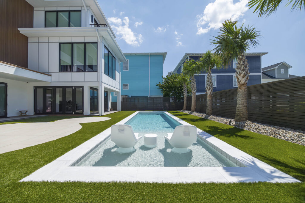 Lounge chairs in a turquoise lap pool in the courtyard of a modern home.