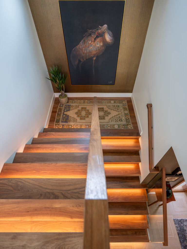 Unique view of a staircase, we are looking down at the u-shaped stairwell with lit rises and unique art on the wall.