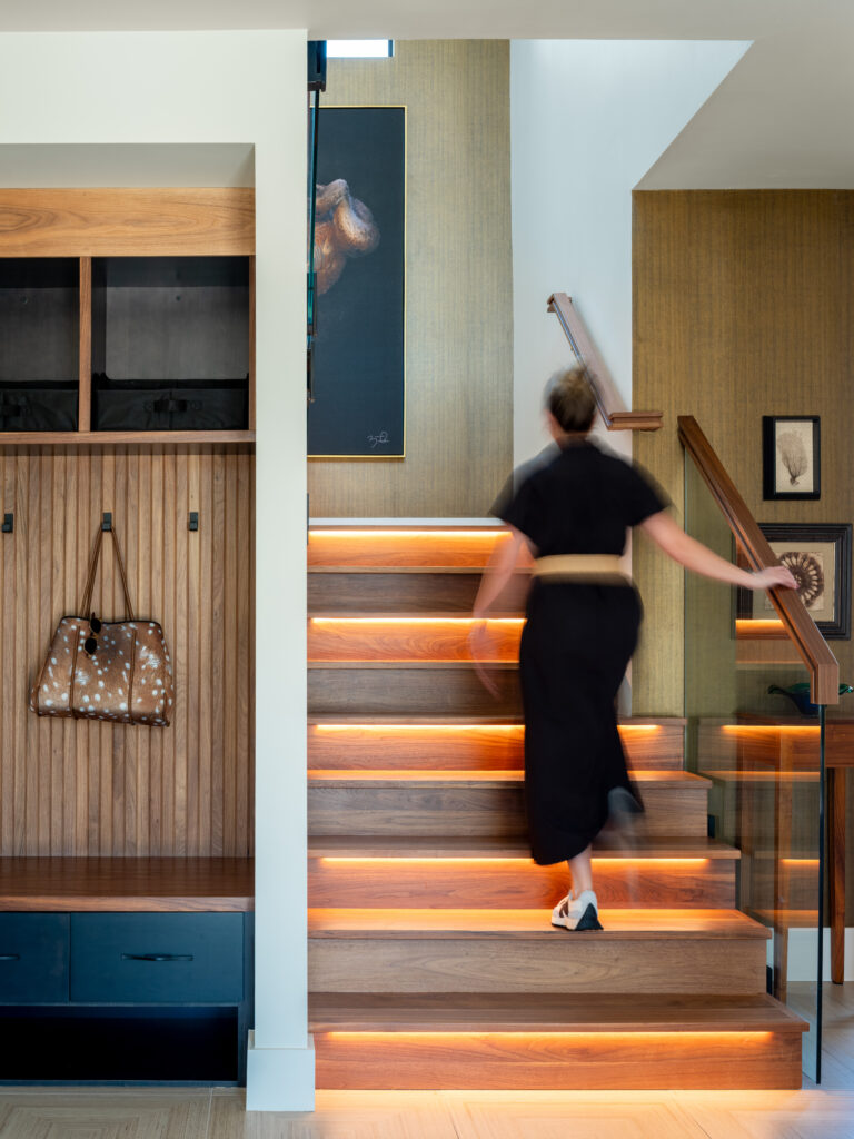A blurry person heads up a modern staircase in a transitional foyer.
