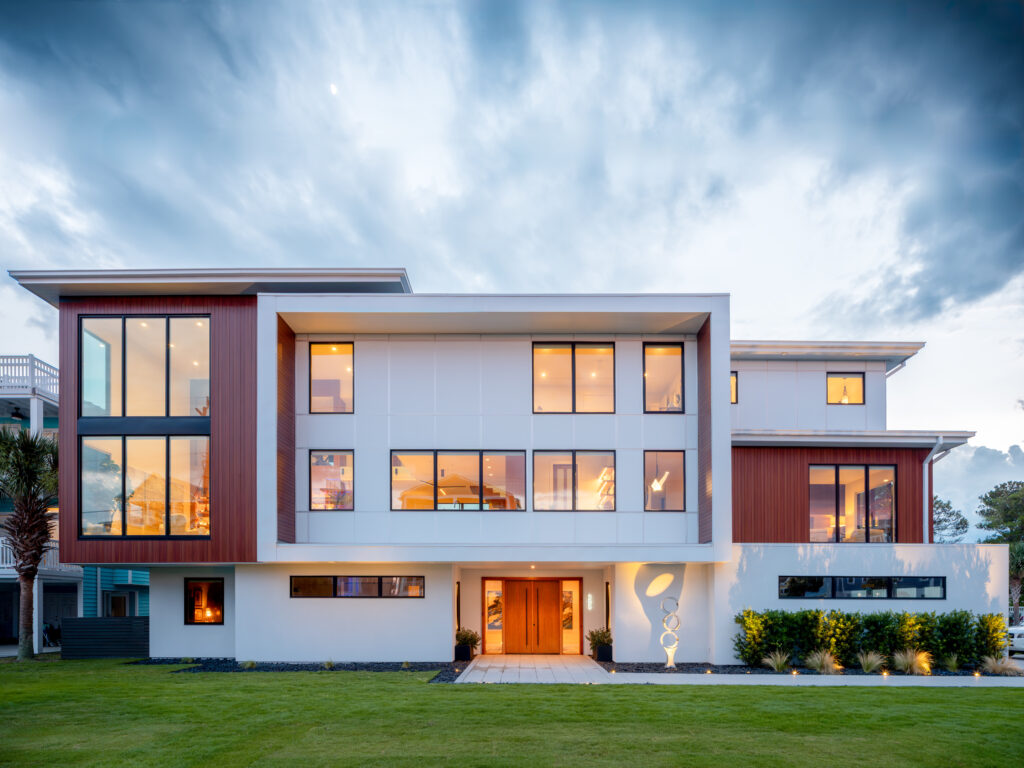 White and brown modern coastal home with boxy exterior shapes at sunset.